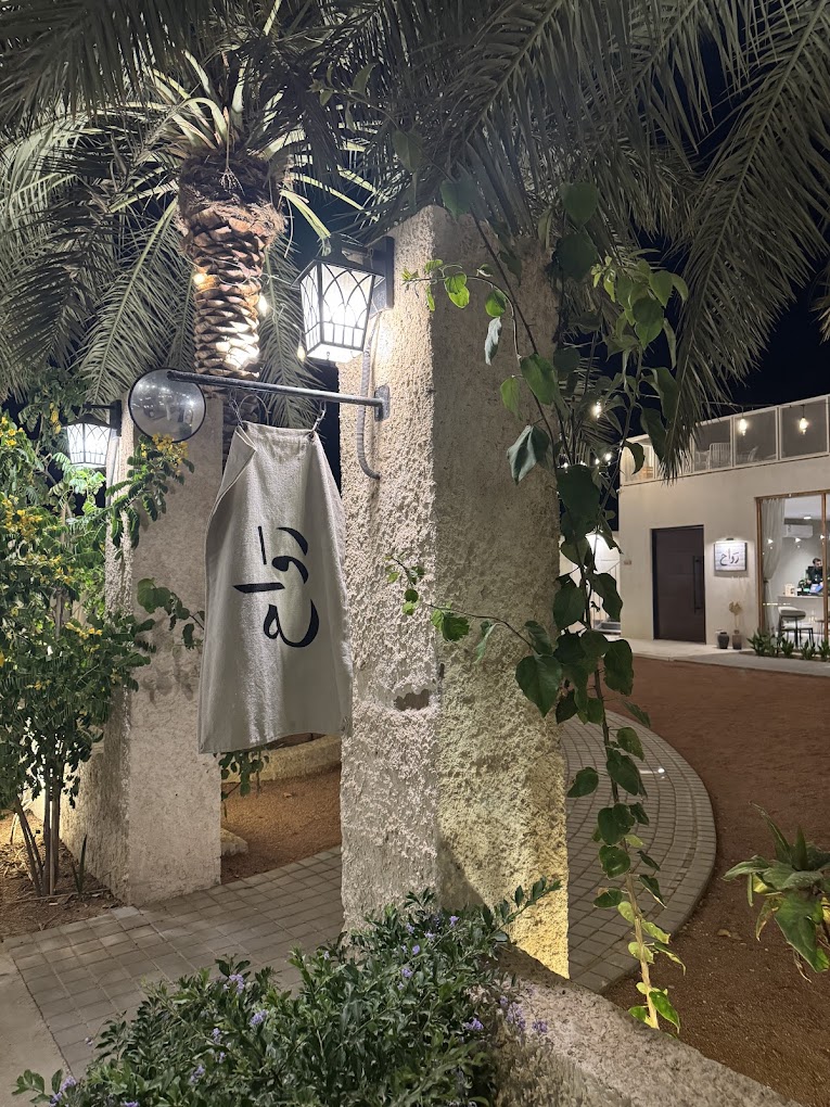 Illuminated stone entrance of rawah with the linen banner between palms