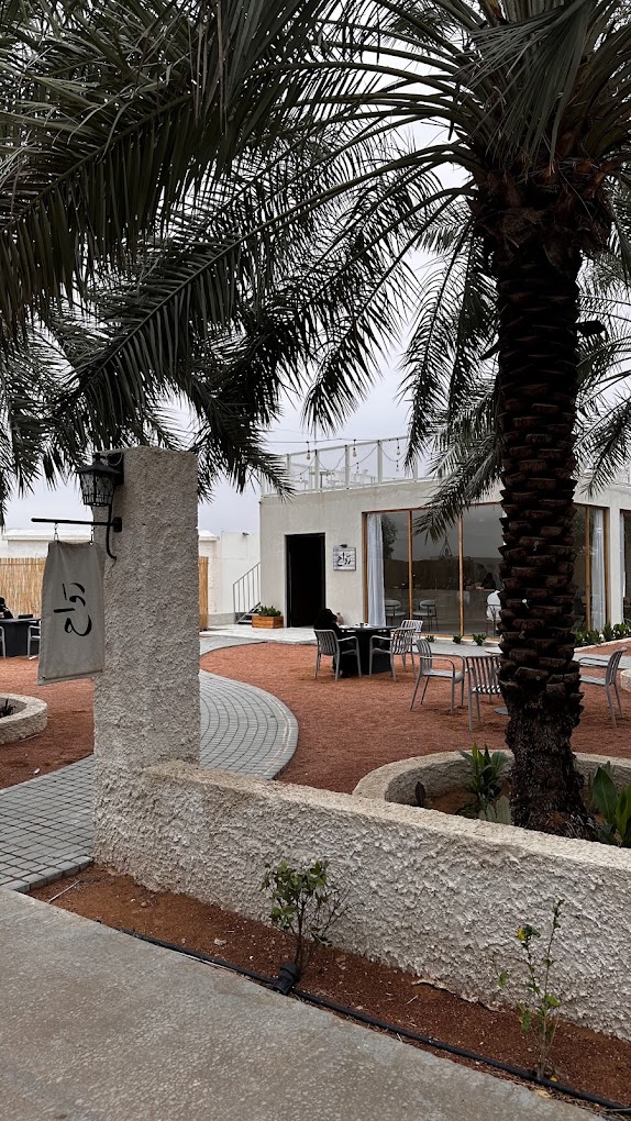 Outdoor garden terrace at rawah with palms, seating and the stone facade