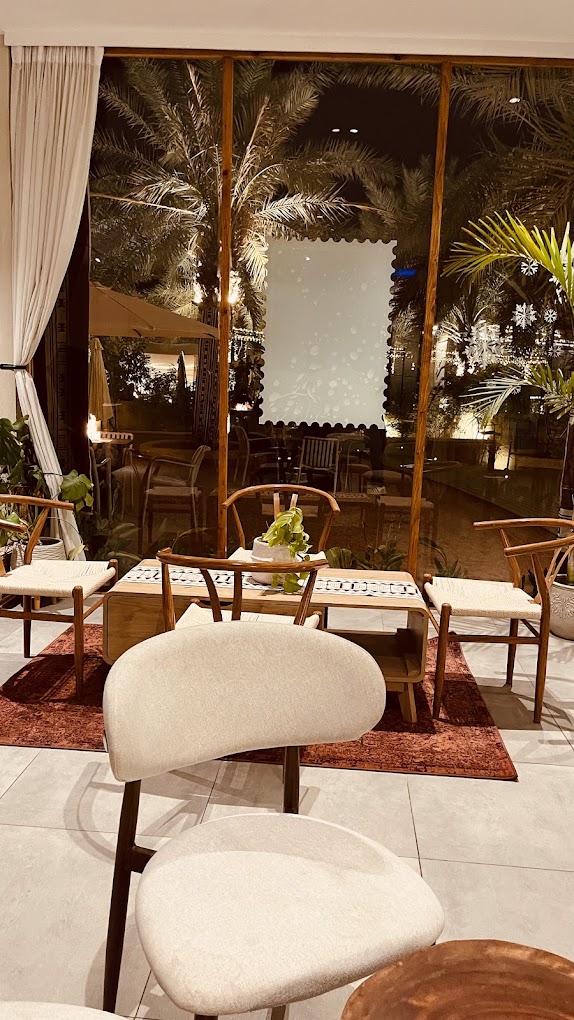 Seating area at rawah at night with palms outside the glass front