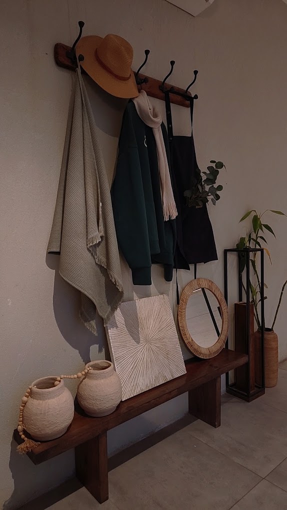 Entrance nook at rawah with wooden bench, ceramics and a rattan mirror